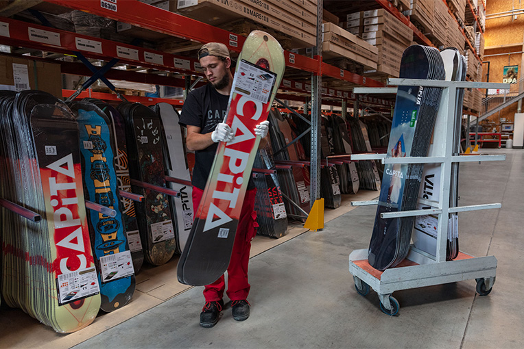 Ein Mann hält ein Snowboard in einer hochmodernen, digital transformierten Fertigungshalle.