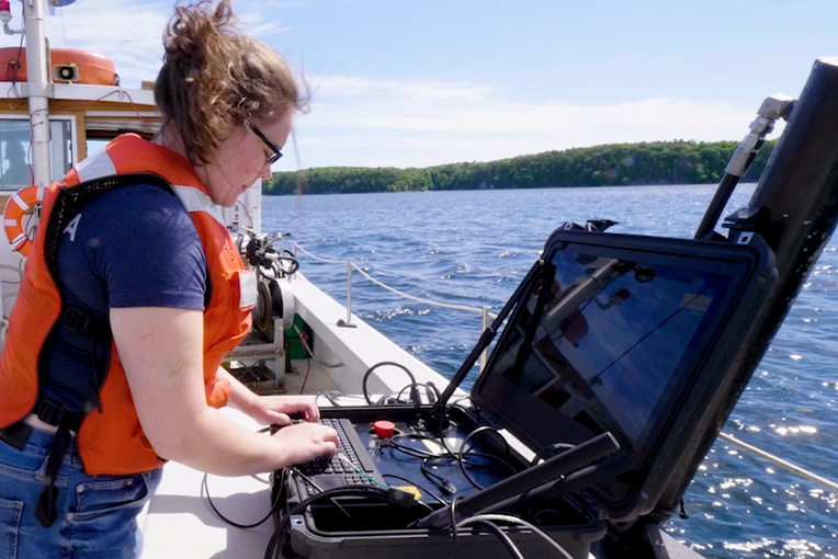 Een vrouw die een onderwaterrobot bedient met een topside-controller.