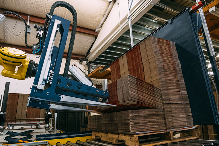 A photo of the box hopper robot lifting corrugated cardboard boxes to move them to the next machine