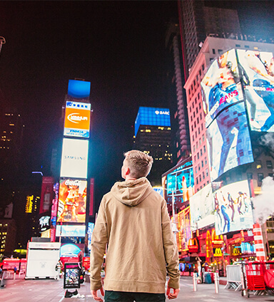 Boy in Times Square admiring large digital signage installation.